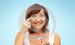 Happy senior woman applying contact lenses