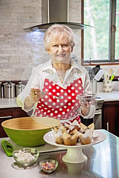 Happy senior woman baking in a bright modern kitchen