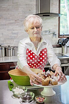 Happy senior woman baking in a bright modern kitchen