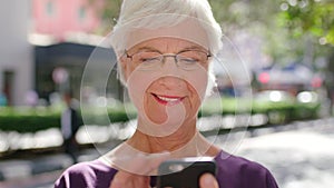 A happy senior woman browsing social media on her phone, smiling and laughing at the viral content online. Mature female