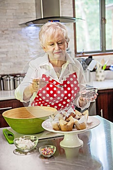 Happy senior woman decorating cupcakes in a bright modern kitchen