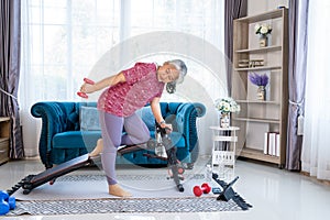 Happy senior woman doing exercise with dumbbells at home