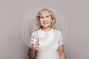 Happy senior woman drinking water. Mature lady holding glass of water