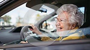 Happy senior woman driving car alone, enjoying car ride. Safe driving for elderly adults, older driver safety.