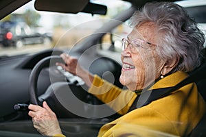 Happy senior woman driving car alone, enjoying car ride. Safe driving for elderly adults, older driver safety.