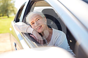 Happy senior woman driving in car with open window