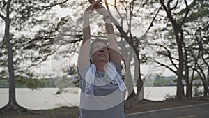 Happy senior woman exercise and stretching at lake park in evening sunset. asian elderly female outdoor activity workout. fitness