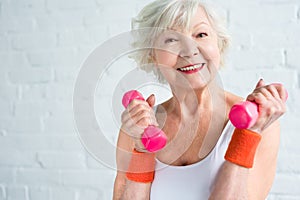 happy senior woman exercising with dumbbells and smiling