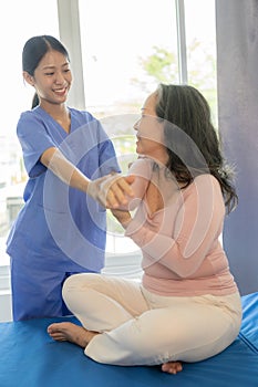 Happy senior woman exercising at home with muscle physiotherapist Retired elderly woman