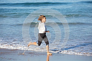 Happy senior woman exercising on sea beach on sunny day