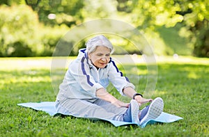 Happy senior woman exercising at summer park