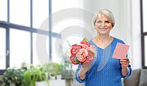 Happy senior woman with flowers and greeting card