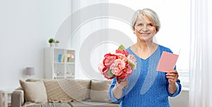 Happy senior woman with flowers and greeting card