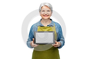 happy senior woman in garden apron with tablet pc