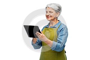 happy senior woman in garden apron with tablet pc