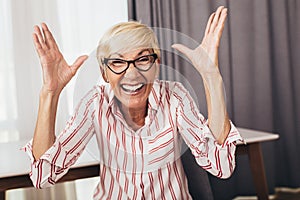 Happy senior woman gesturing by hands at home