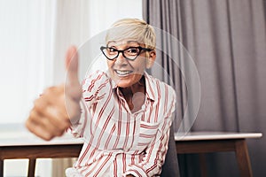 Happy senior woman gesturing by hands at home