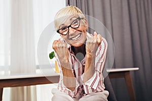 Happy senior woman gesturing by hands at home