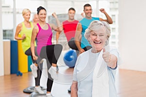 Happy senior woman gesturing thumbs up at gym