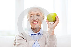 Happy senior woman with green apple at home