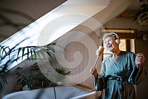 Happy senior woman with headphones singing at home, relax and self-care concept.