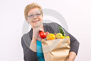 Happy senior woman holding fruits and vegetables in shopping bag, healthy nutrition in old age