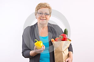 Happy senior woman holding fruits and vegetables in shopping bag, healthy nutrition in old age