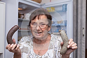 Happy senior woman holding pork liver sausages