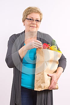 Happy senior woman holding shopping bag with fruits and vegetables, healthy nutrition in old age