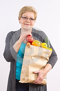 Happy senior woman holding shopping bag with fruits and vegetables, healthy nutrition in old age