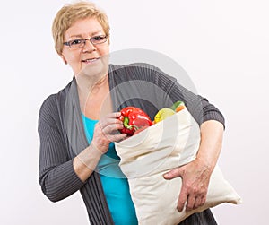 Happy senior woman holding shopping bag with fruits and vegetables, healthy nutrition in old age