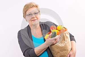 Happy senior woman holding shopping bag with fruits and vegetables, healthy nutrition in old age