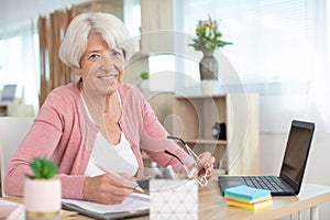 Happy senior woman holding smartphone and laptop