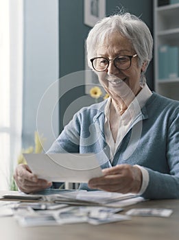 Happy senior woman looking at her old pictures