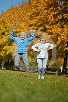 Happy senior woman and man in park jumping