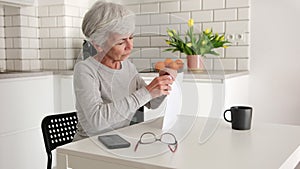 Happy Senior Woman Opens Envelope With Documents And Papers At Home