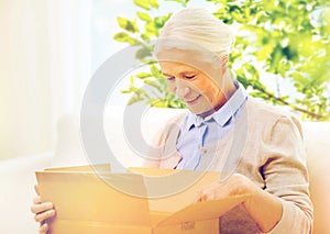 Happy senior woman with parcel box at home