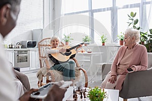 Happy senior woman playing acoustic guitar