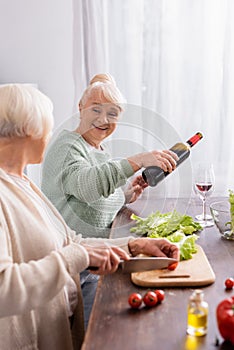 happy senior woman pouring red wine