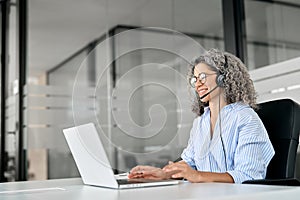 Happy senior woman professional call contact center agent working in office.