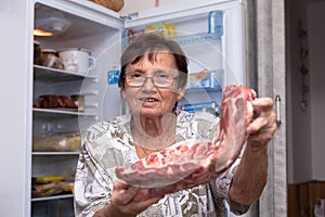 Happy senior woman with raw pork ribs