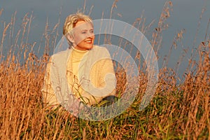 Happy senior woman relaxing in the high grass in nature