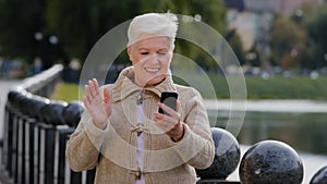 Happy senior woman of retirement age making video call, looking at smartphone camera. Attractive old mature female uses