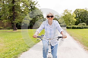 Happy senior woman riding bicycle at summer park