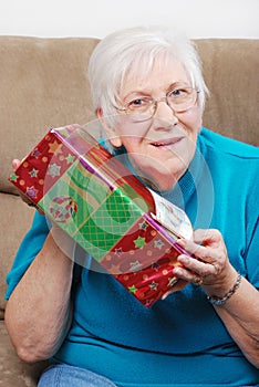 Happy senior woman shaking her christmas present