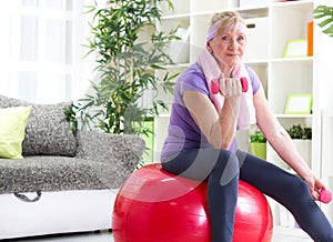 Happy senior woman sitting on gym ball, and exercise