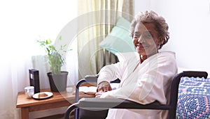 Happy senior woman sitting in wheelchair at nursing home