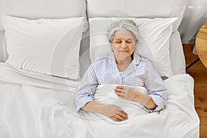 happy senior woman sleeping in bed at home bedroom