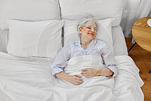 happy senior woman sleeping in bed at home bedroom