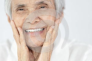 Happy senior woman is smiling confidently at beauty of new denture,false teeth in her mouth,beautiful old elderly showing new